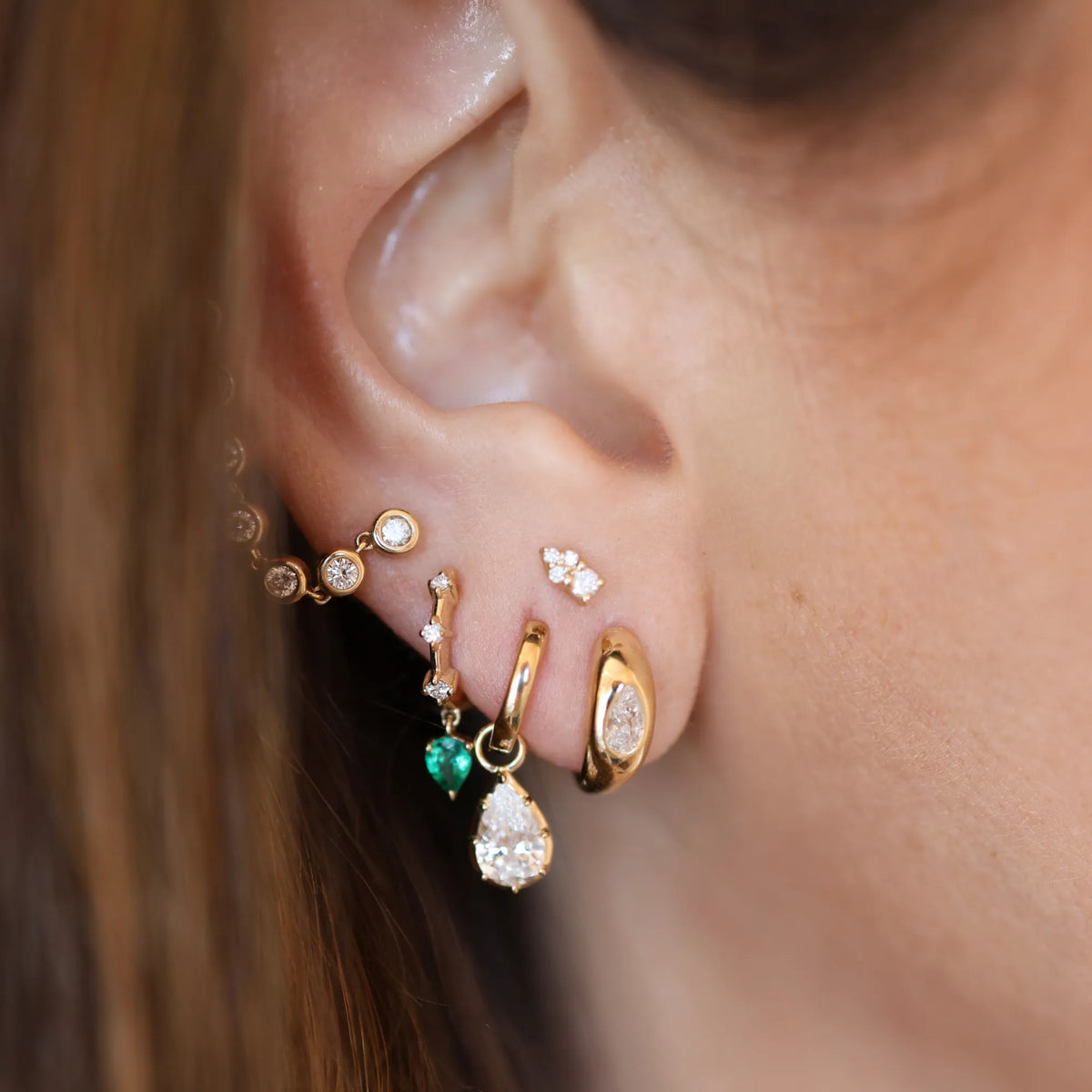 14k yellow gold ear stack with pear diamond and sapphire huggie earrings, diamond studs, and emerald drop, handmade jewelry by Mama Bijoux Costa Mesa Orange County