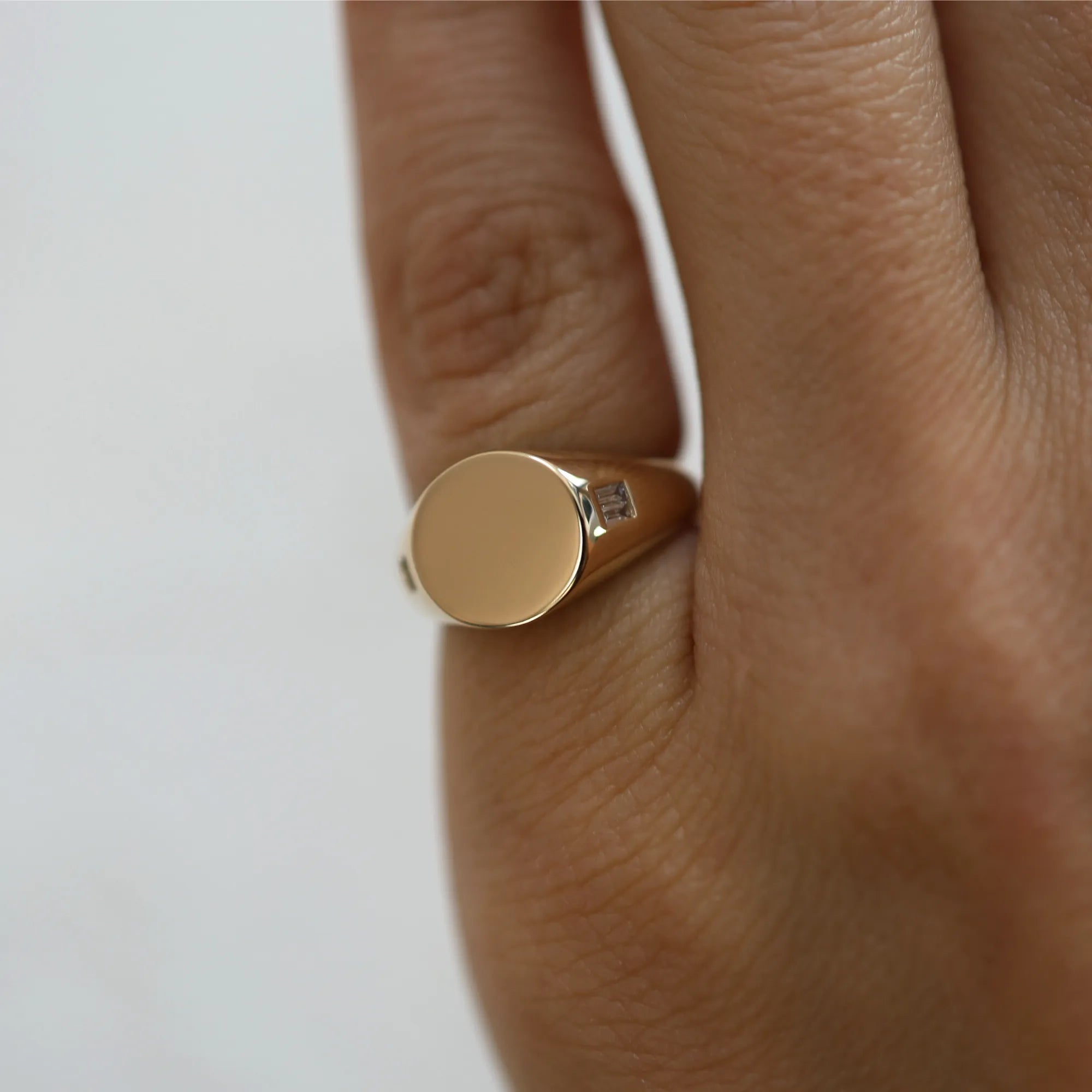 Gold ring with a diamond on a finger against a white background