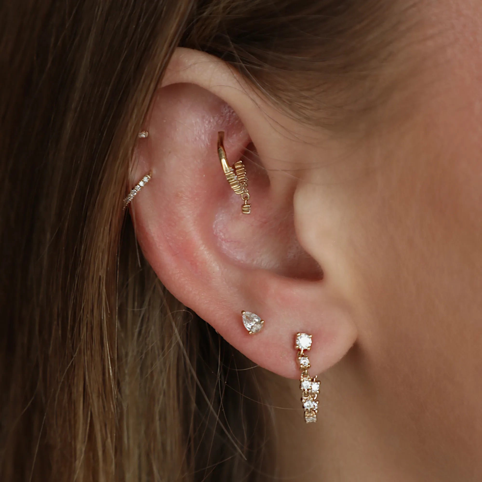 Close-up of an ear with gold and diamond earrings