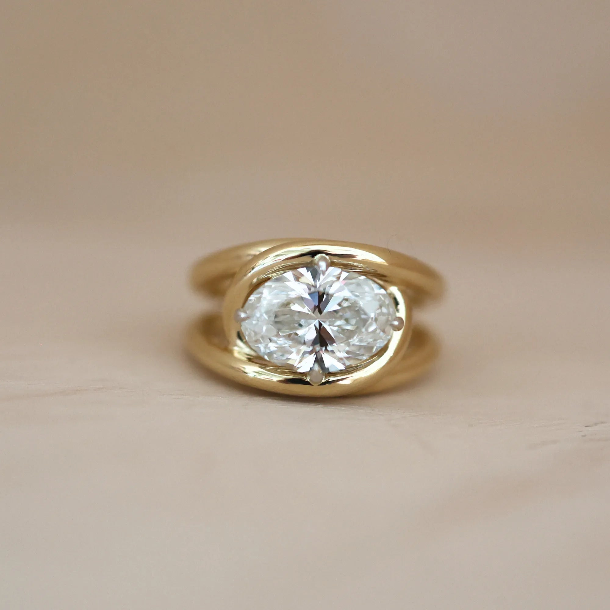 Gold ring with a large diamond on a beige background
