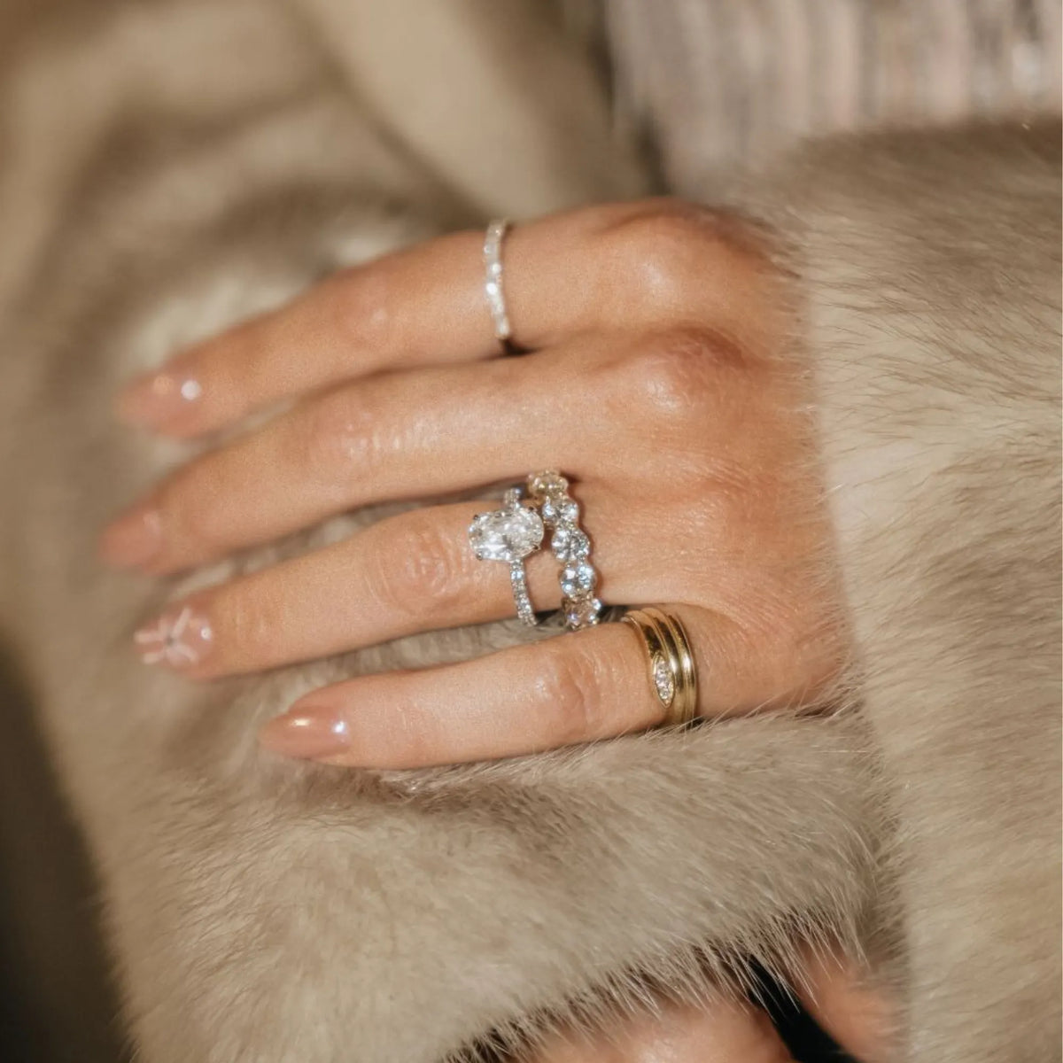 Close-up of a hand wearing multiple rings on a fur surface