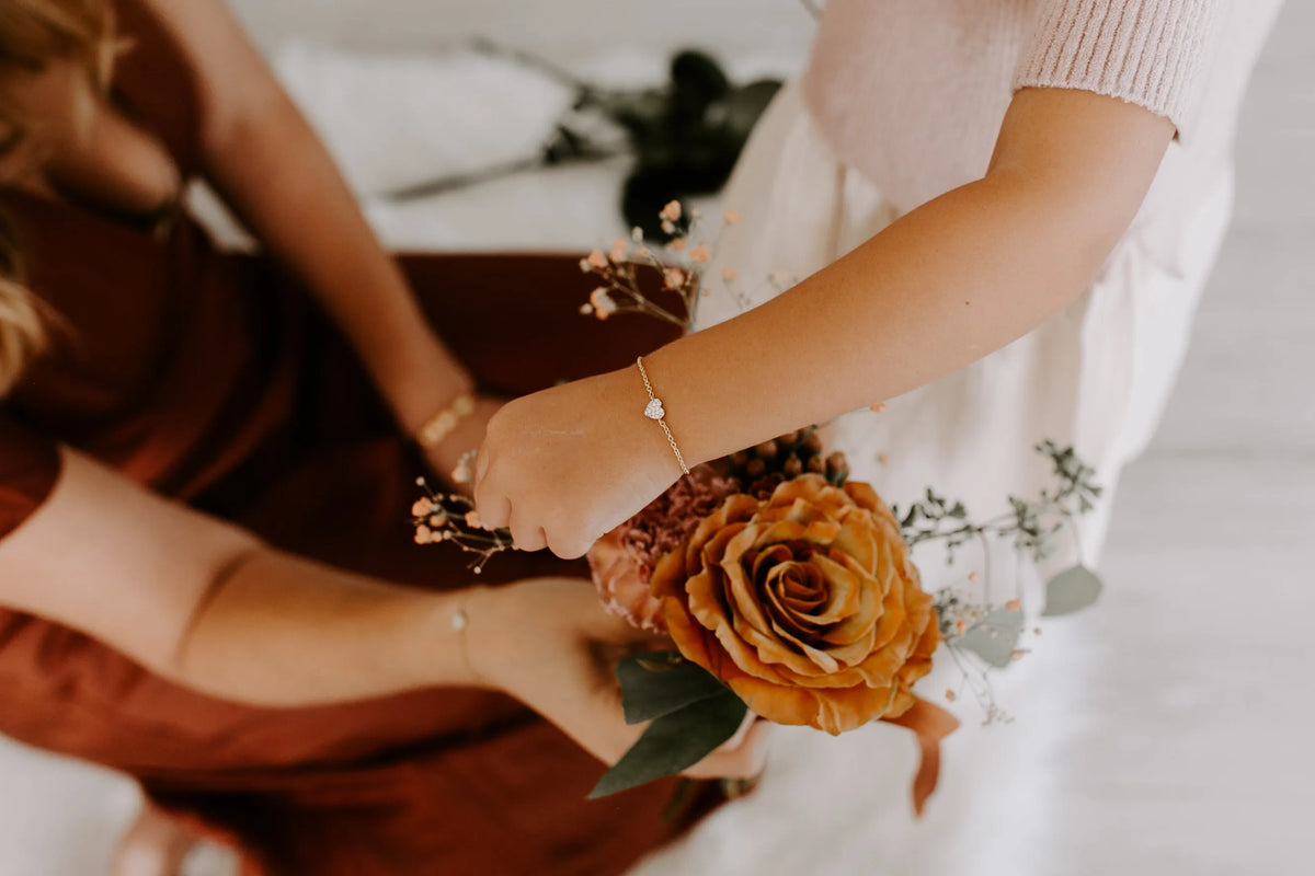 Mom & Babe Matching Diamond Heart Bracelet Set in 18k yellow gold: child wearing the bracelet while holding a rose bouquet