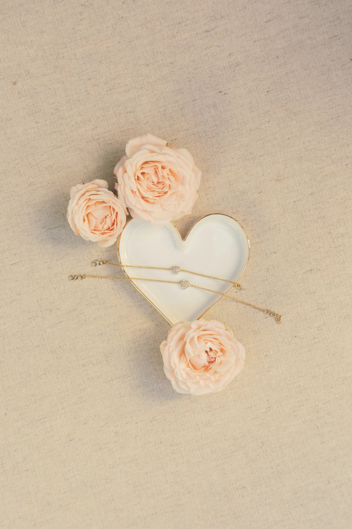 Mom & Babe Matching Diamond Heart Bracelet Set in 18k yellow gold: adult and baby bracelets in a heart-shaped dish with roses