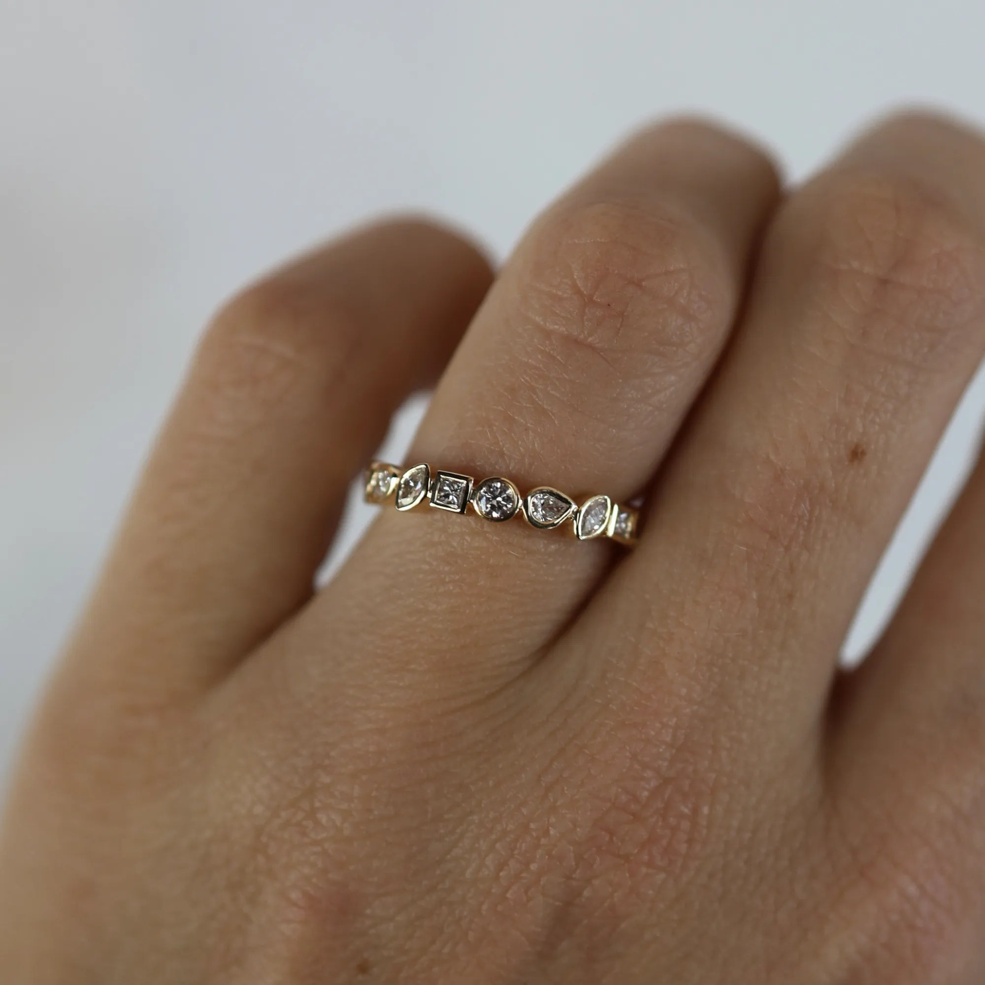 Gold ring with heart-shaped gemstones on a hand against a white background