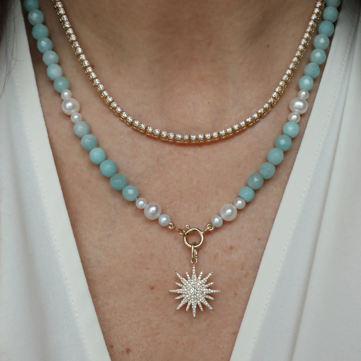 a diamond tennis necklace adn beaded necklace on a woman
