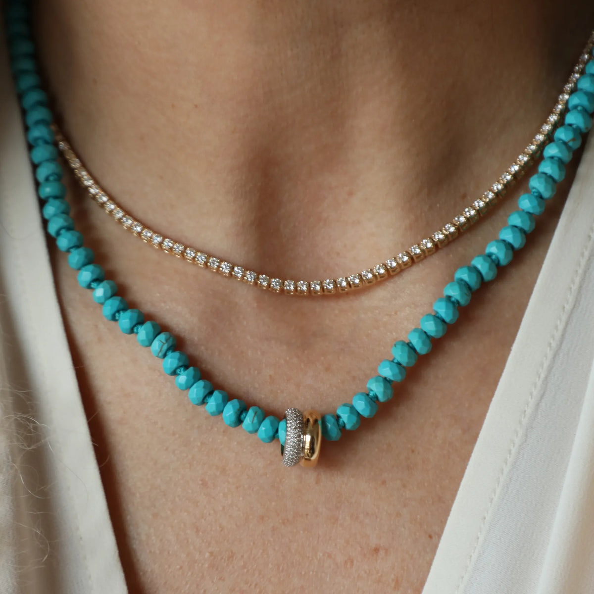 Turquoise beaded necklace with gold clasp worn by a person