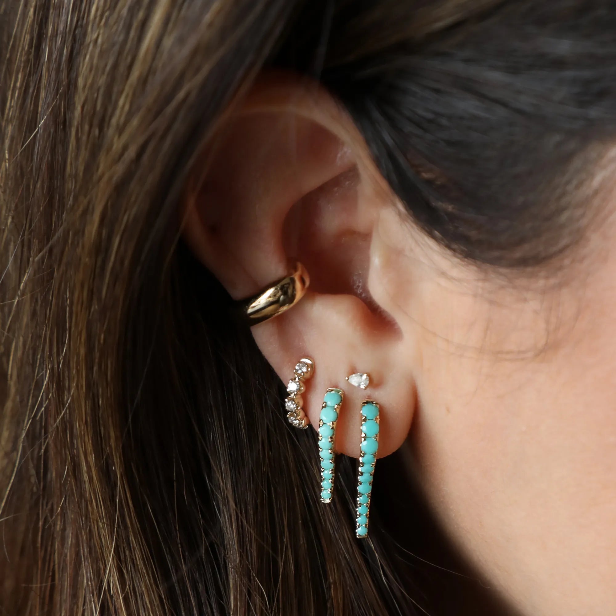 turquoise earrings and diamond earrings on a woman's ear