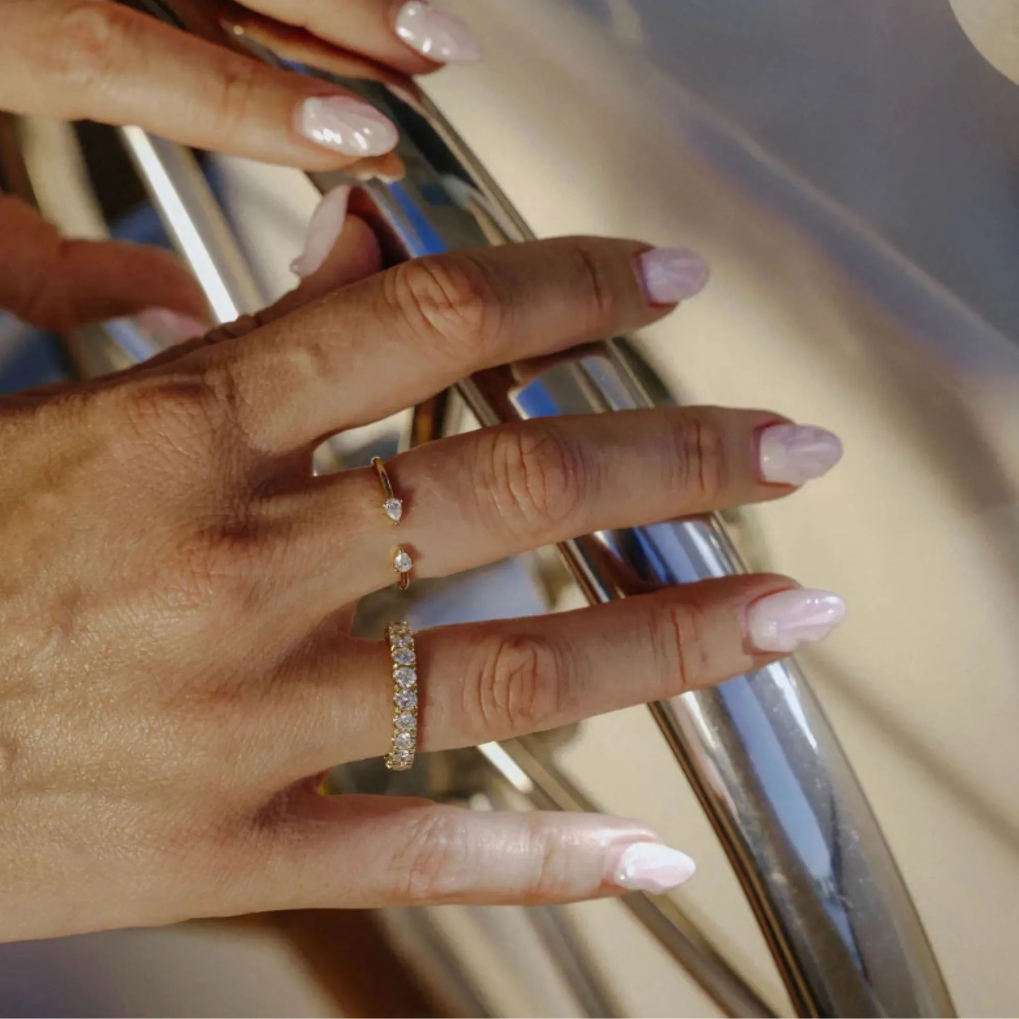 Close-up of a hand with a diamond ring on a metallic surface
