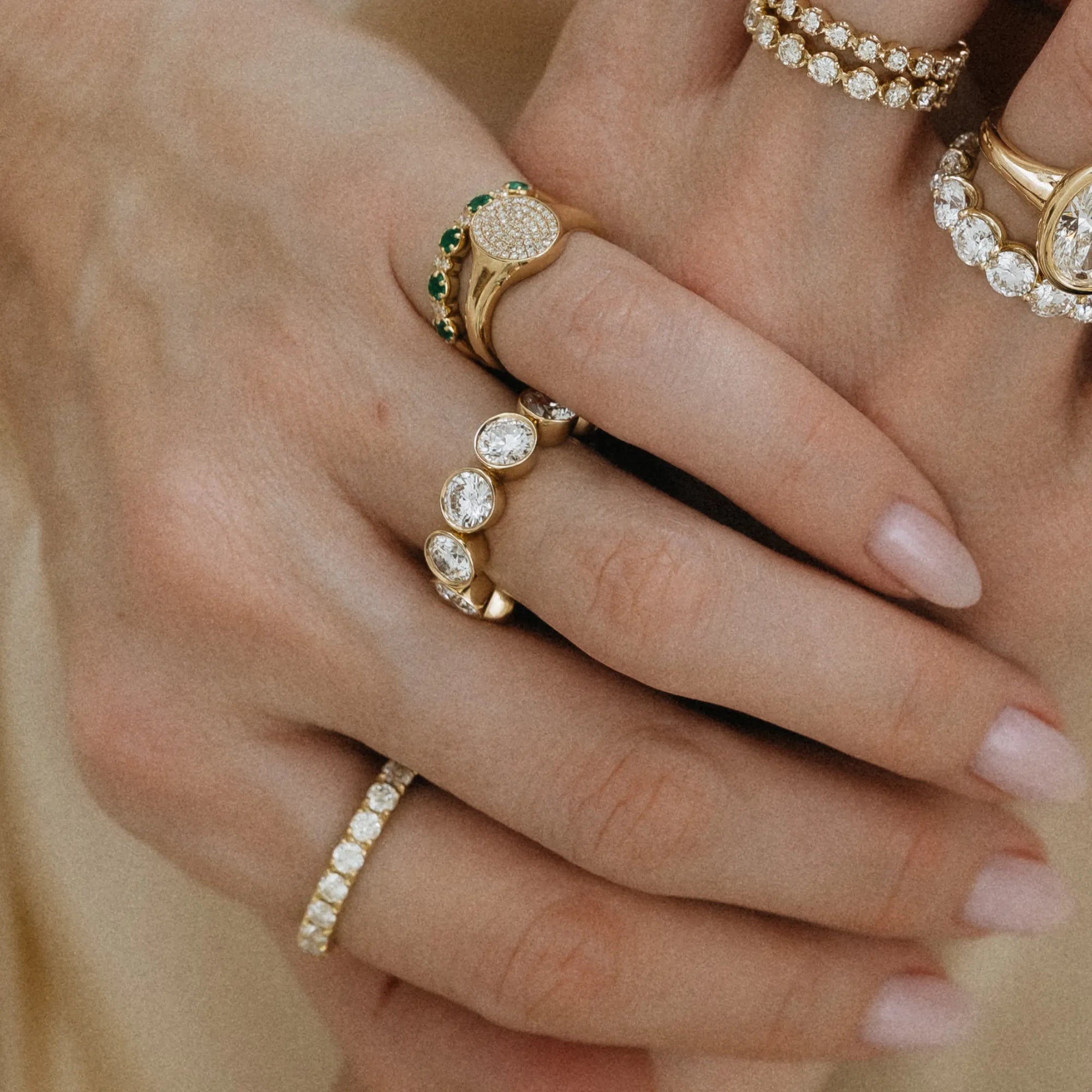 Classic bezel set diamond eternity band in curated ring stack with large bezel diamond ring emerald signet ring and diamond bands 14k yellow gold Mama Bijoux Costa Mesa