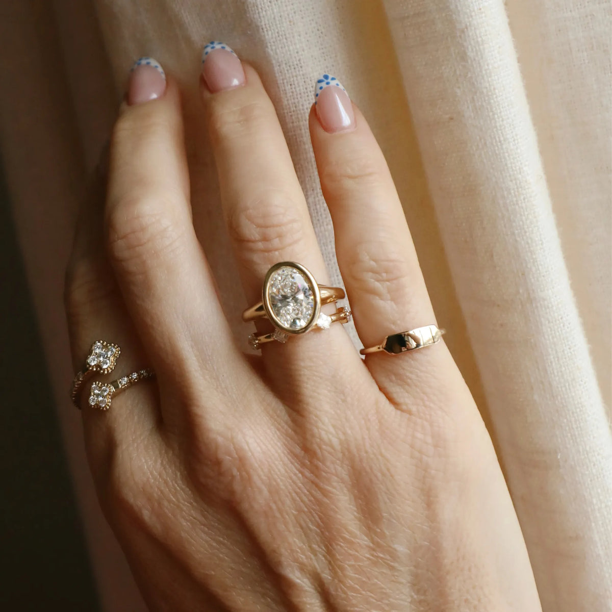 Woman wearing a dainty 14k yellow gold bar signet ring styled with stacked gold rings for an everyday look.