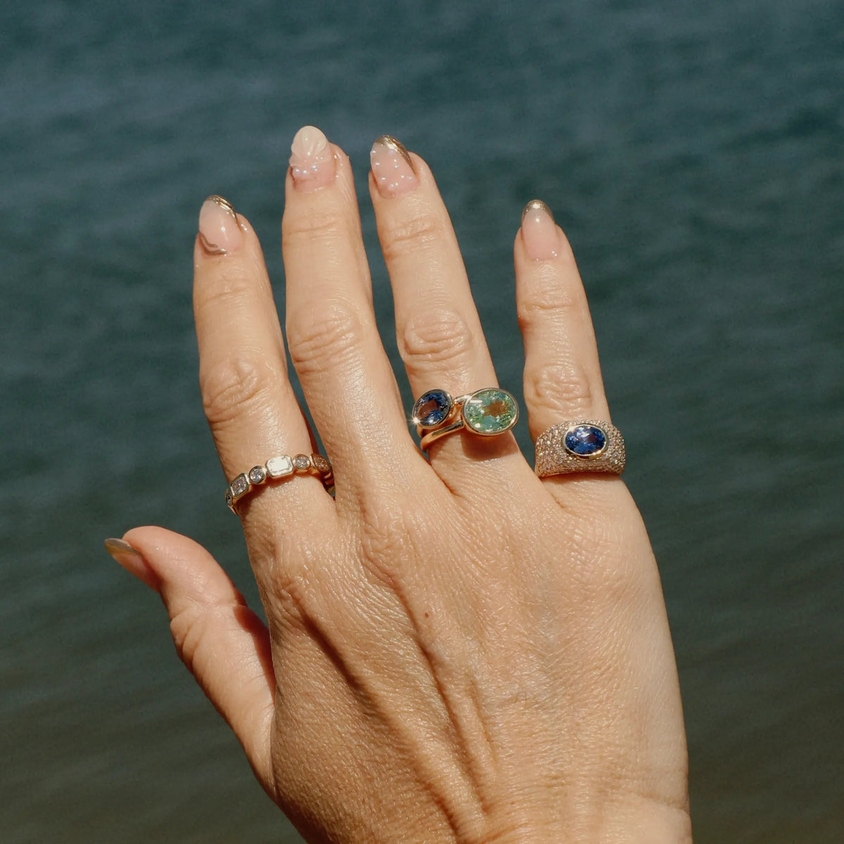 Light blue sapphire pinky ring worn on the hand, featuring a substantial pavé cigar band and oval blue sapphire