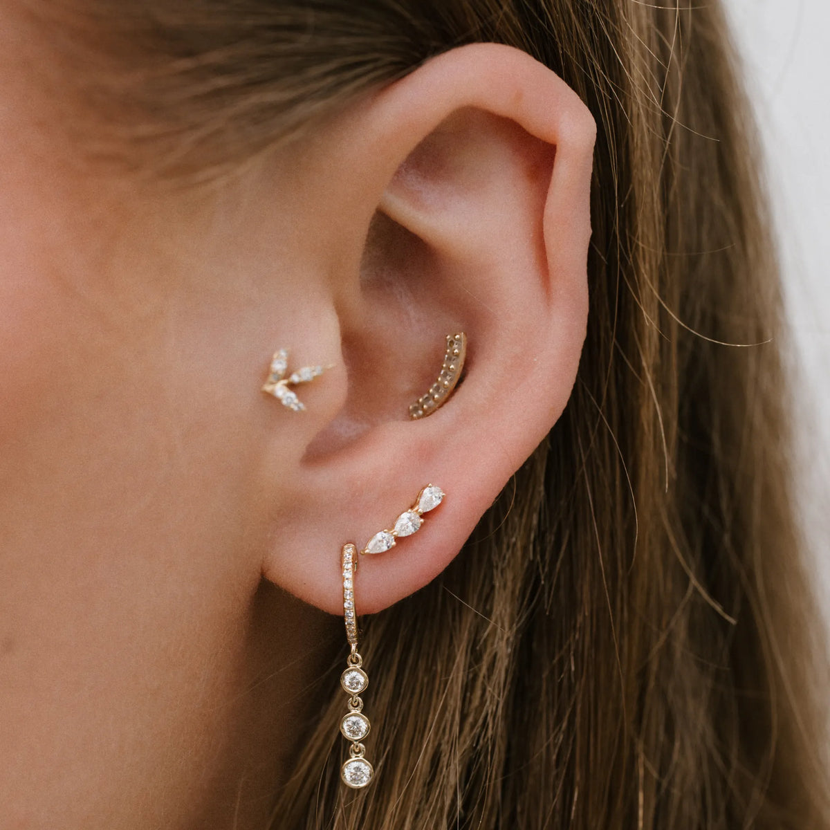 Pear three stone diamond crawler earring worn along the ear with stud stack, everyday earrings by Mama Bijoux Orange County