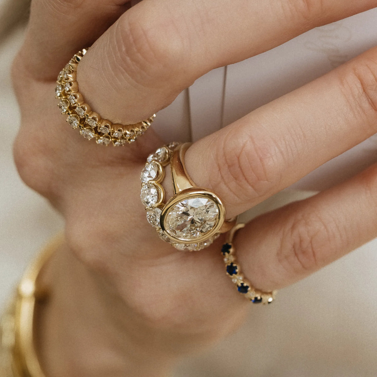 U set shared prong lab diamond eternity band stacked with oval bezel diamond engagement ring and sapphire diamond band 14k yellow gold Mama Bijoux Costa Mesa