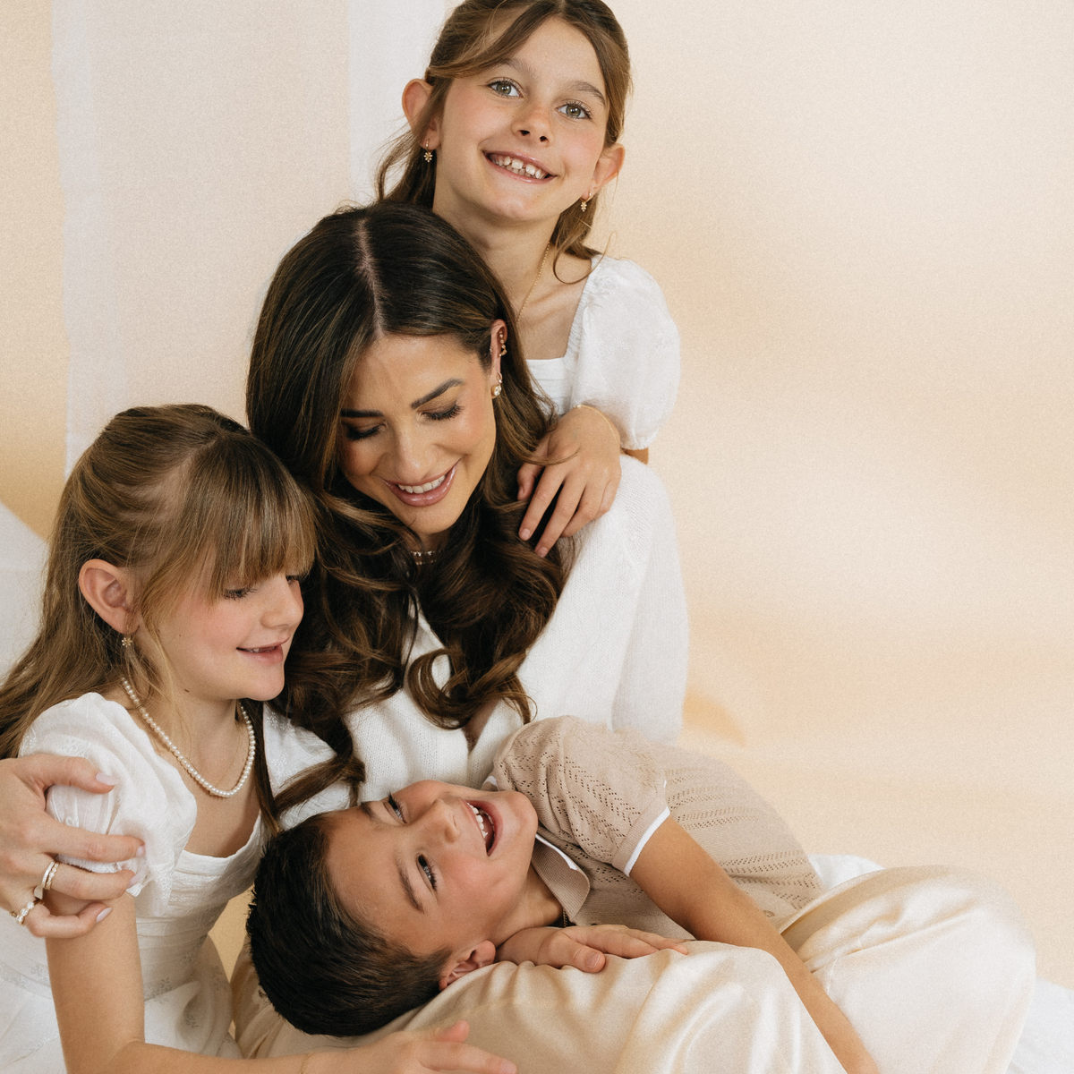 Mother and three children laughing together wearing Mama Bijoux fine gold jewelry