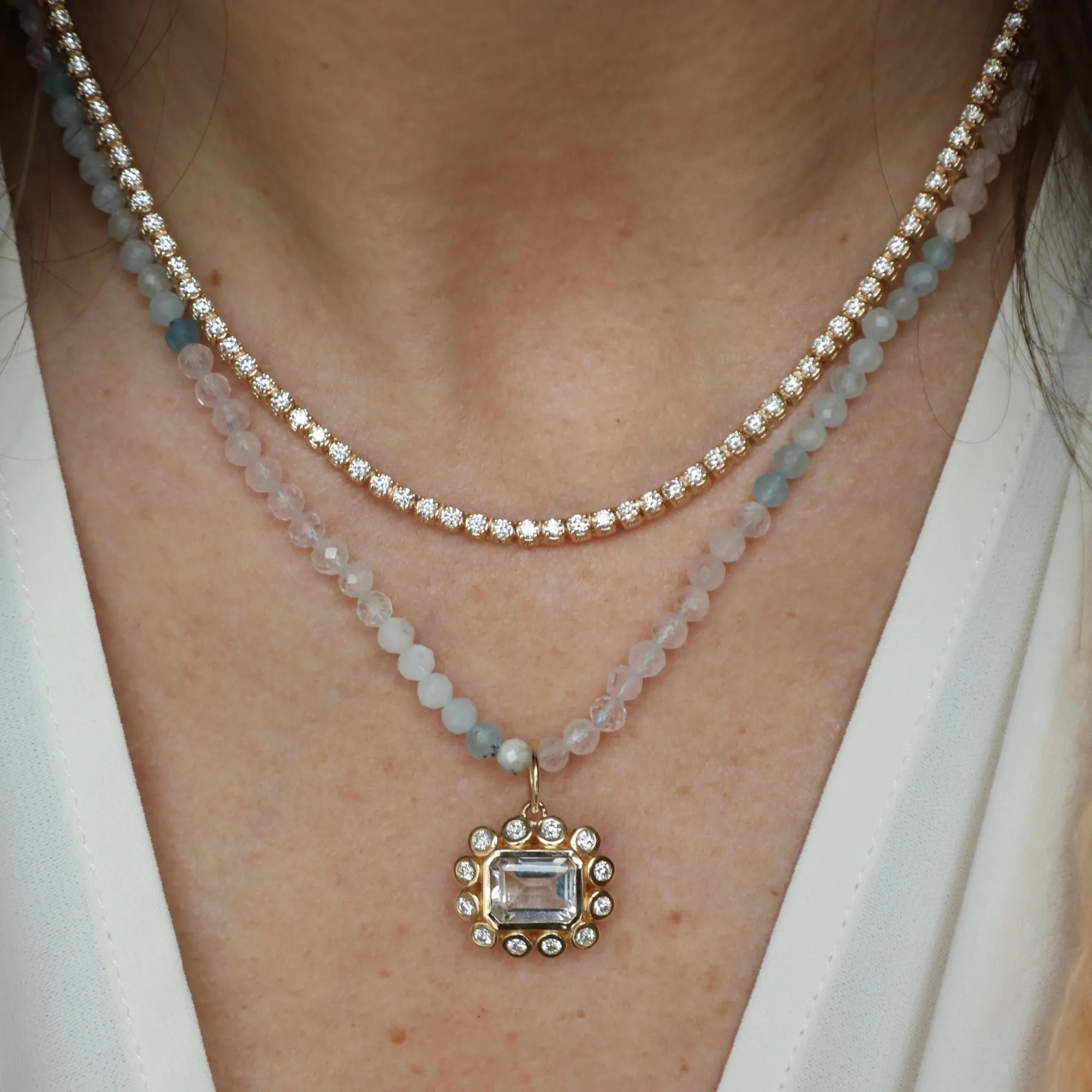 Close-up of a person wearing two necklaces with a prominent pendant.