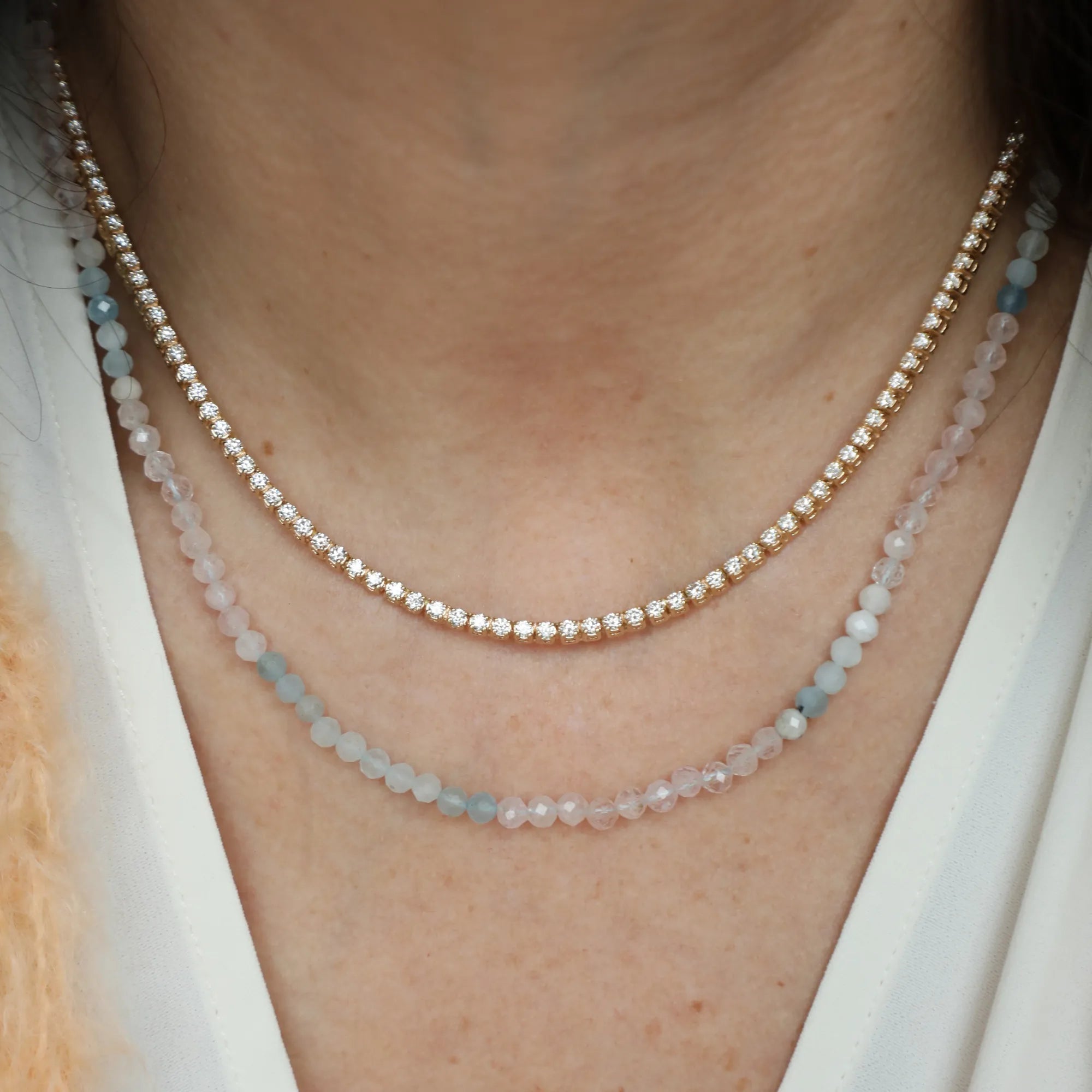 Gold ring with a diamond on a person's finger against a neutral background