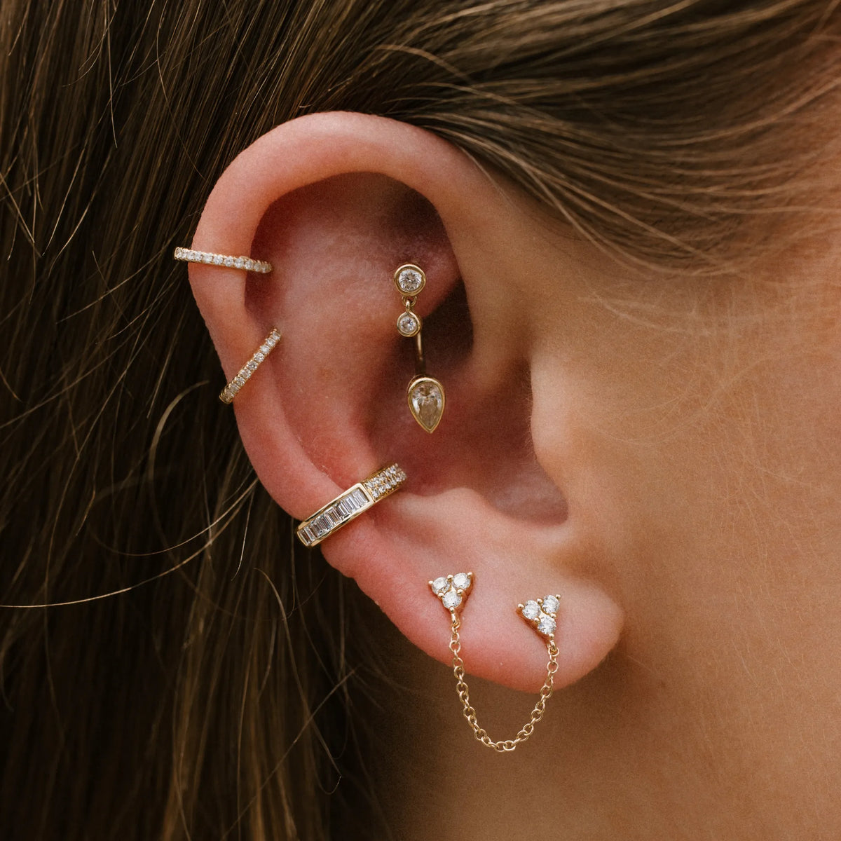 Woman wearing 14k gold diamond trio double stud earring in double piercing with curated ear stack, single stud earring Mama Bijoux