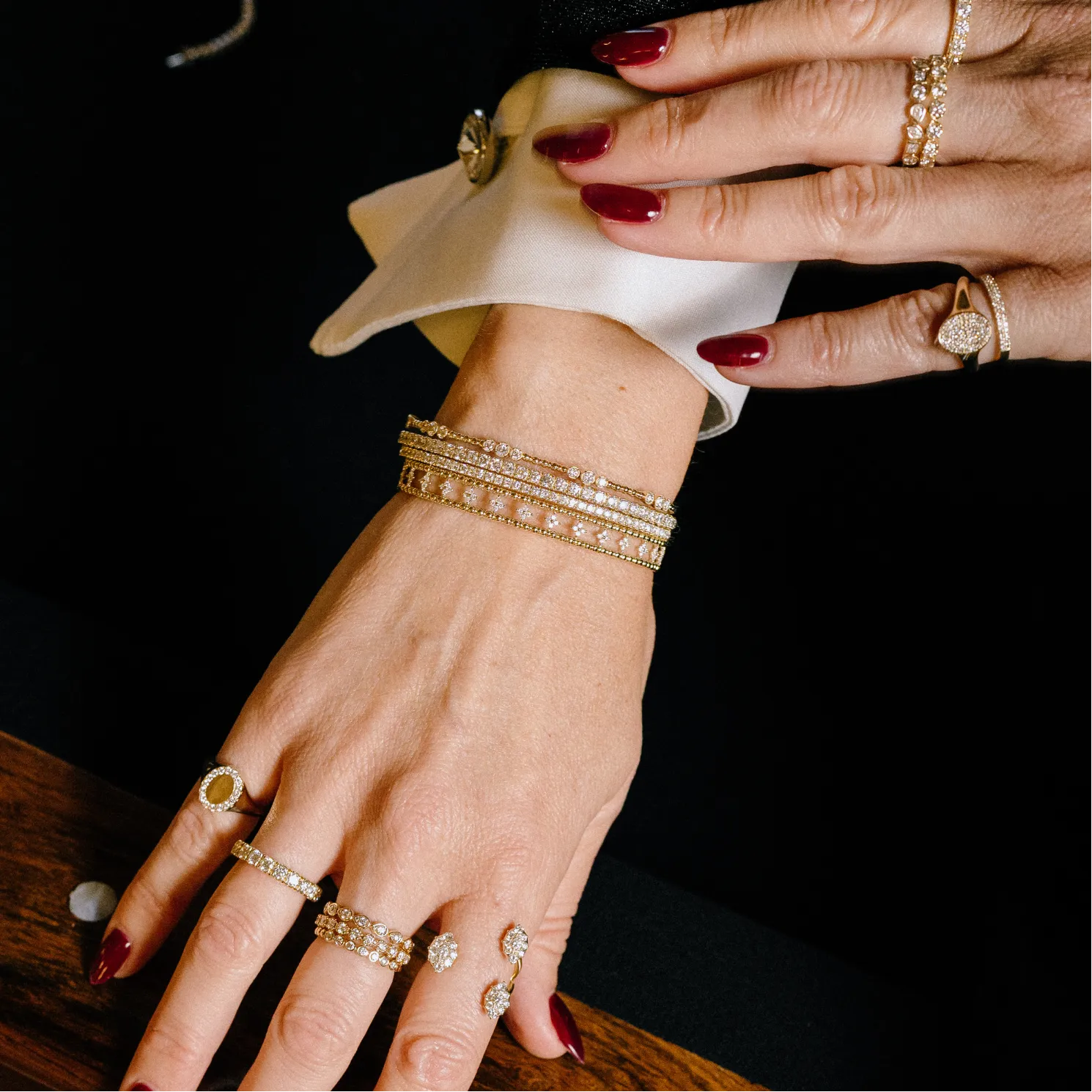 Close-up of a hand with multiple gold rings and bracelets on a dark background