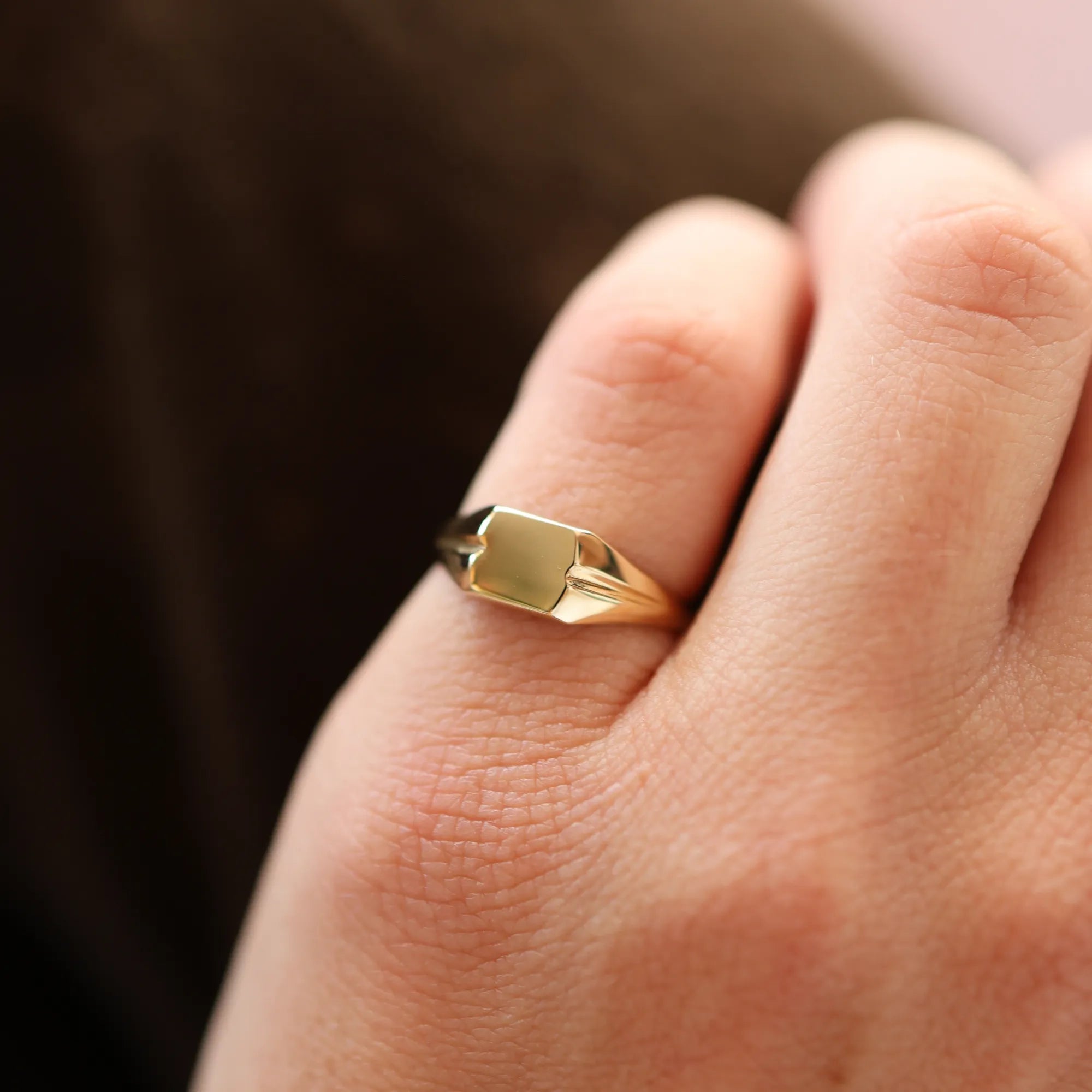 Gold ring on a person's finger with a blurred background
