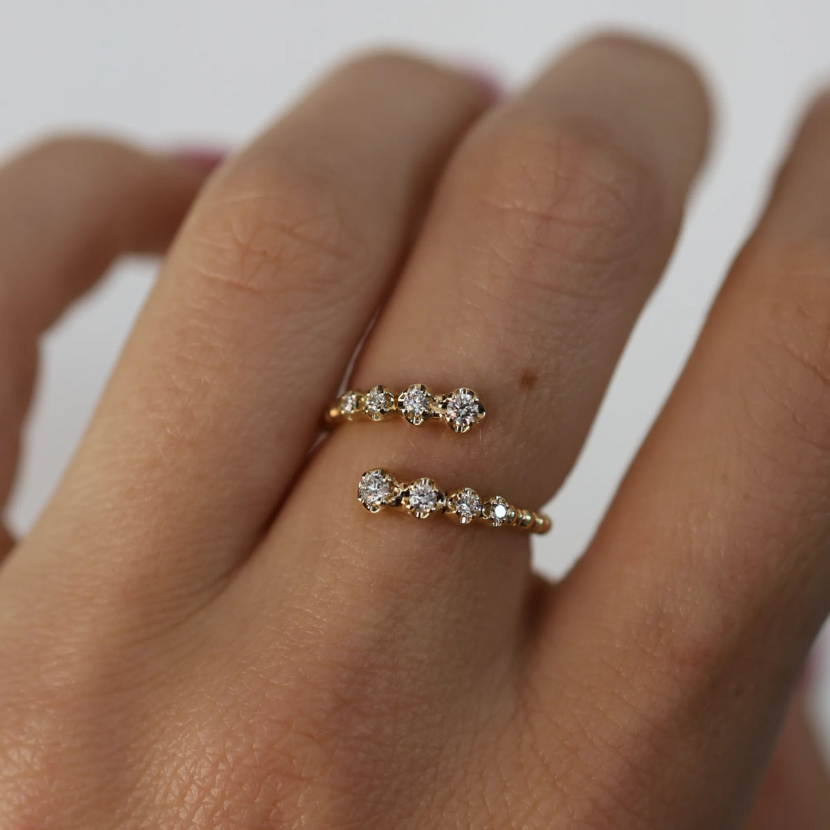 Rose gold ring with diamonds on a finger against a white background