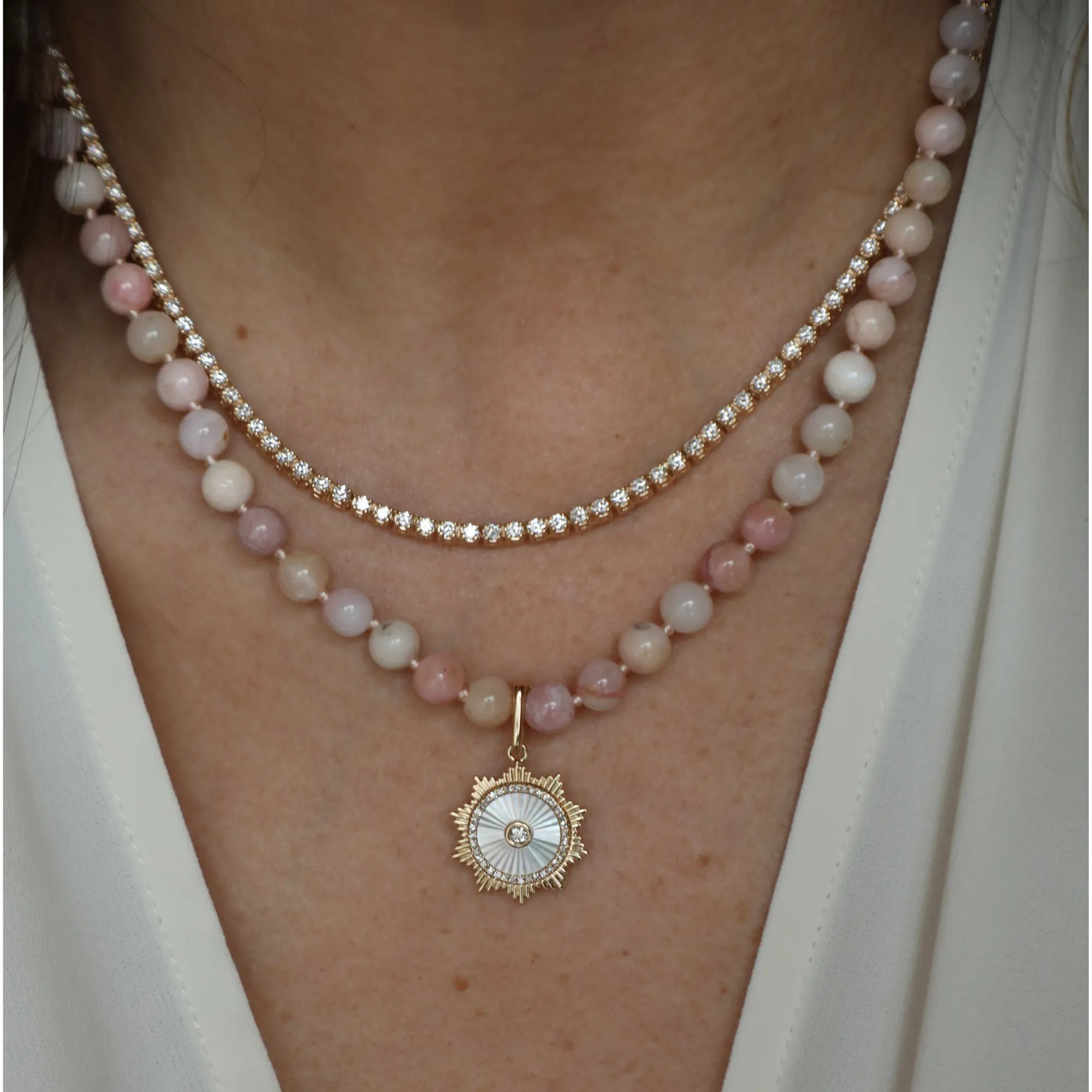 Close-up of a person wearing two pearl necklaces with a gold pendant.