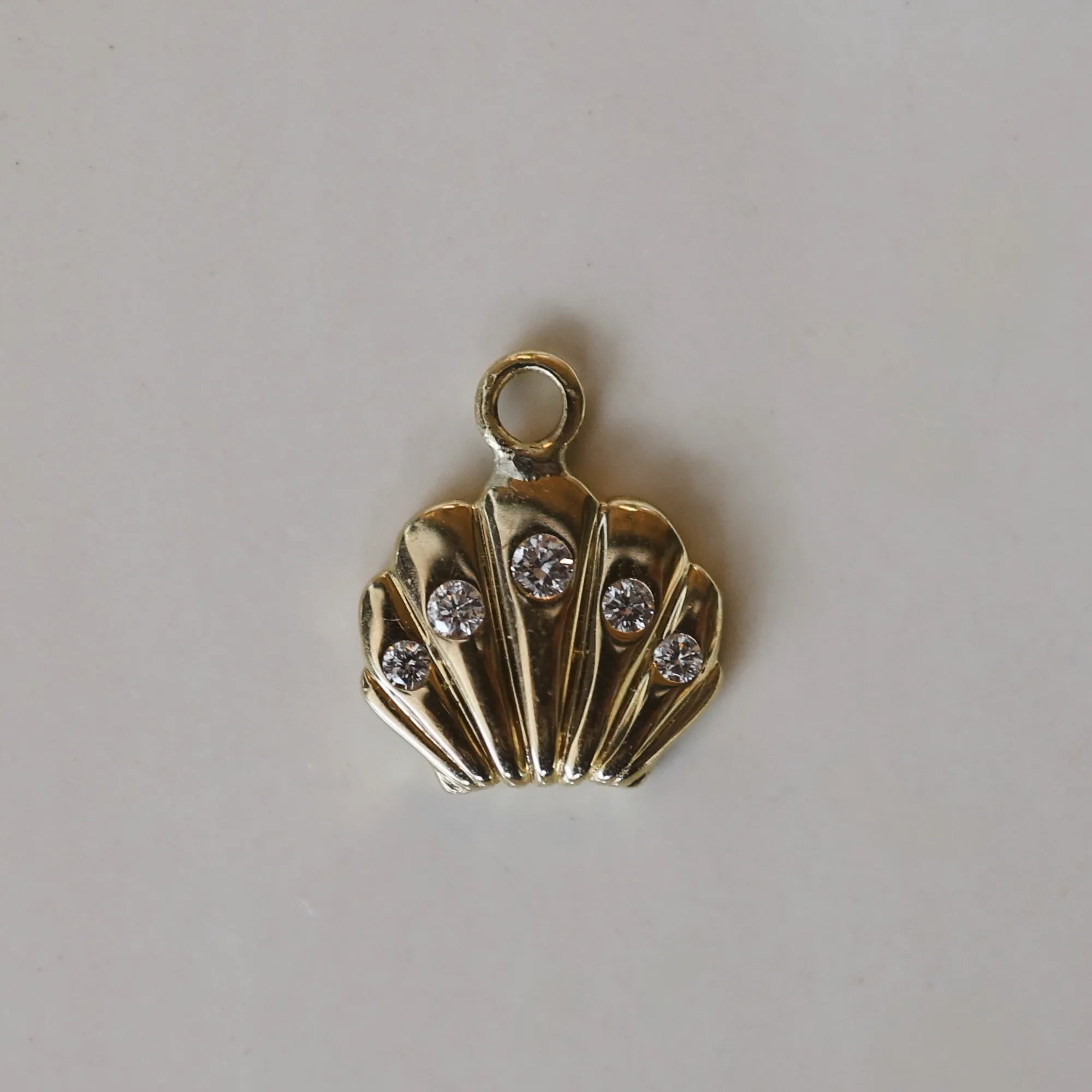 seashell charm with diamonds against a white background