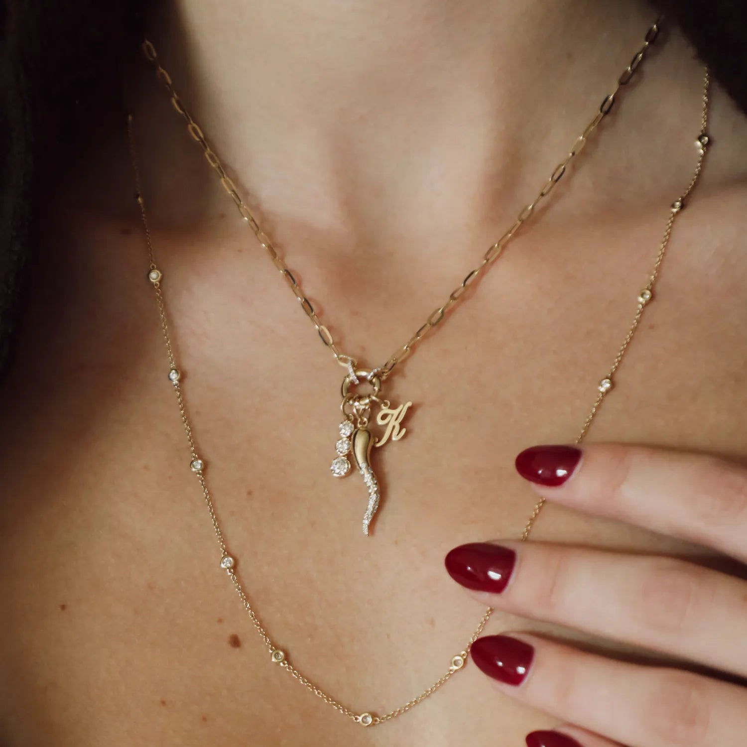 Close-up of a person wearing a gold necklace with a letter 'K' pendant.