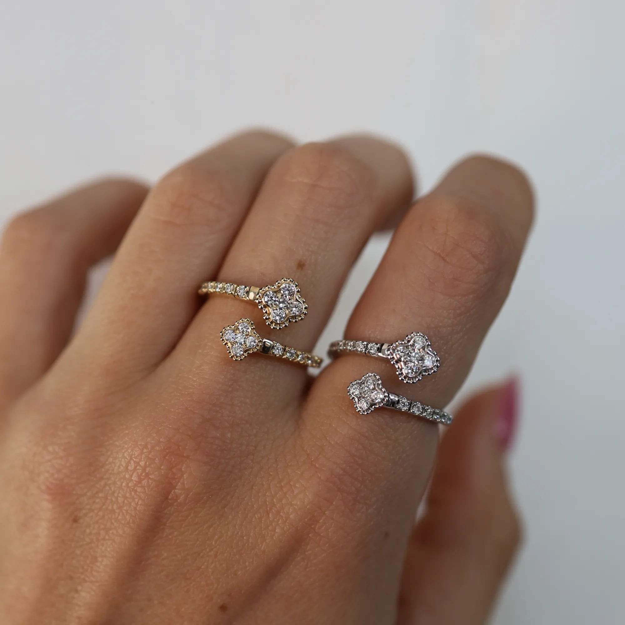 Hand wearing two diamond rings on a neutral background
