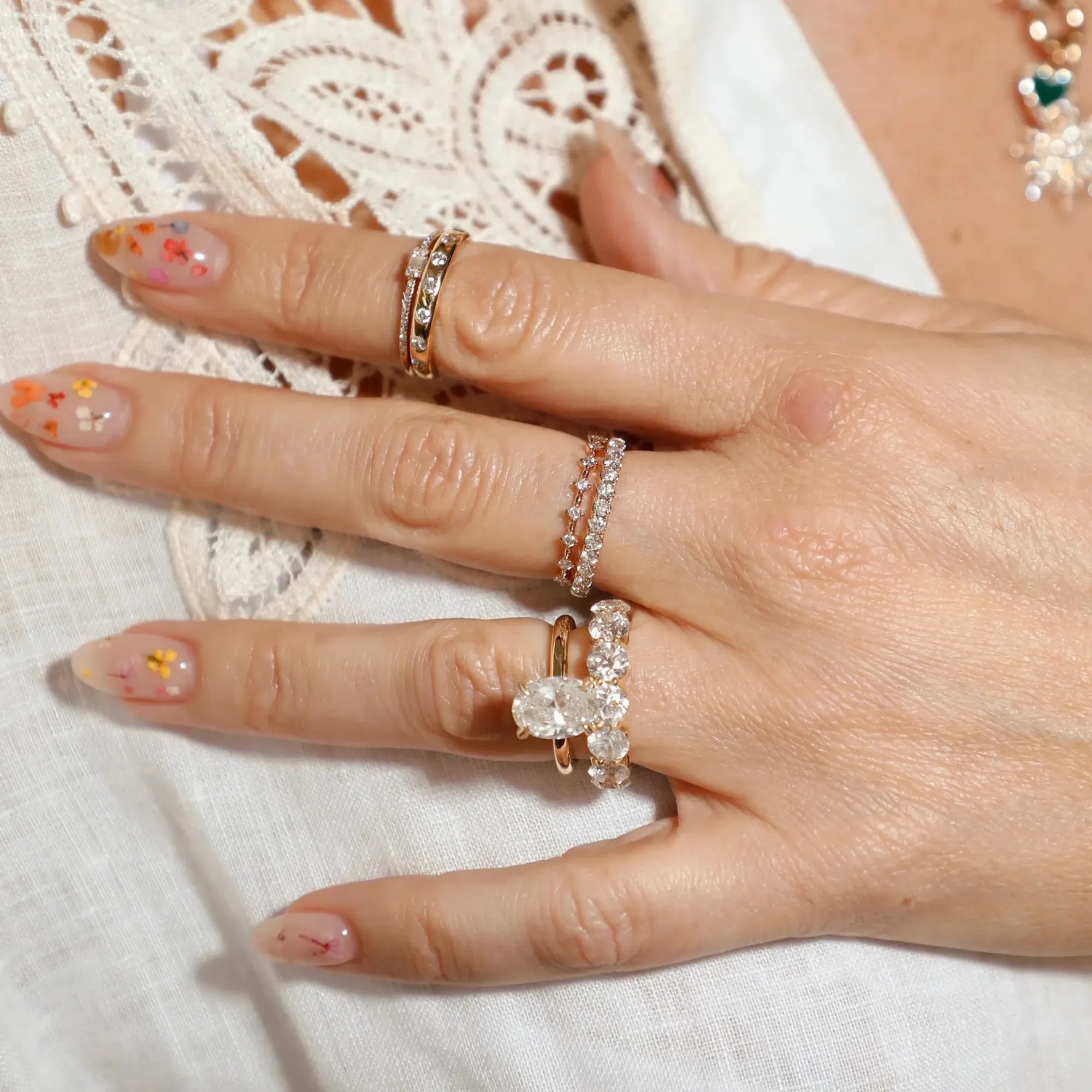 Hand wearing multiple rings with a decorative background