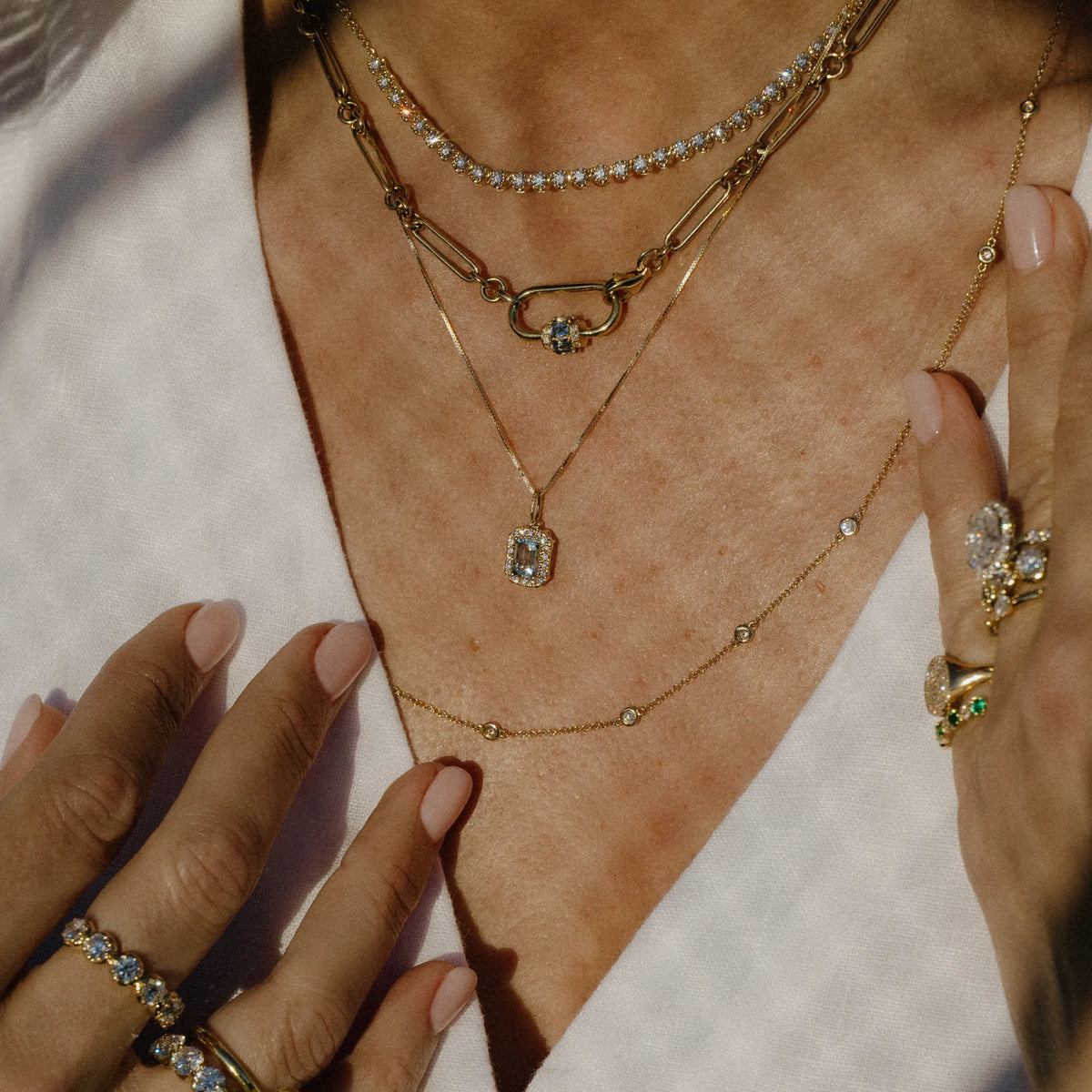 Aquamarine diamond halo charm layered with a gold necklace stack, dainty layered necklace styling by Mama Bijoux Orange County