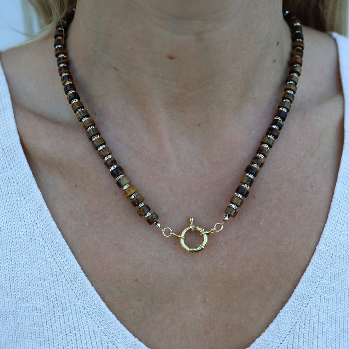 Model wearing the Driftwood Glow tiger's eye beaded necklace by Mama Bijoux x Isla Sol featuring natural tiger's eye gemstones and rhinestone accents.
