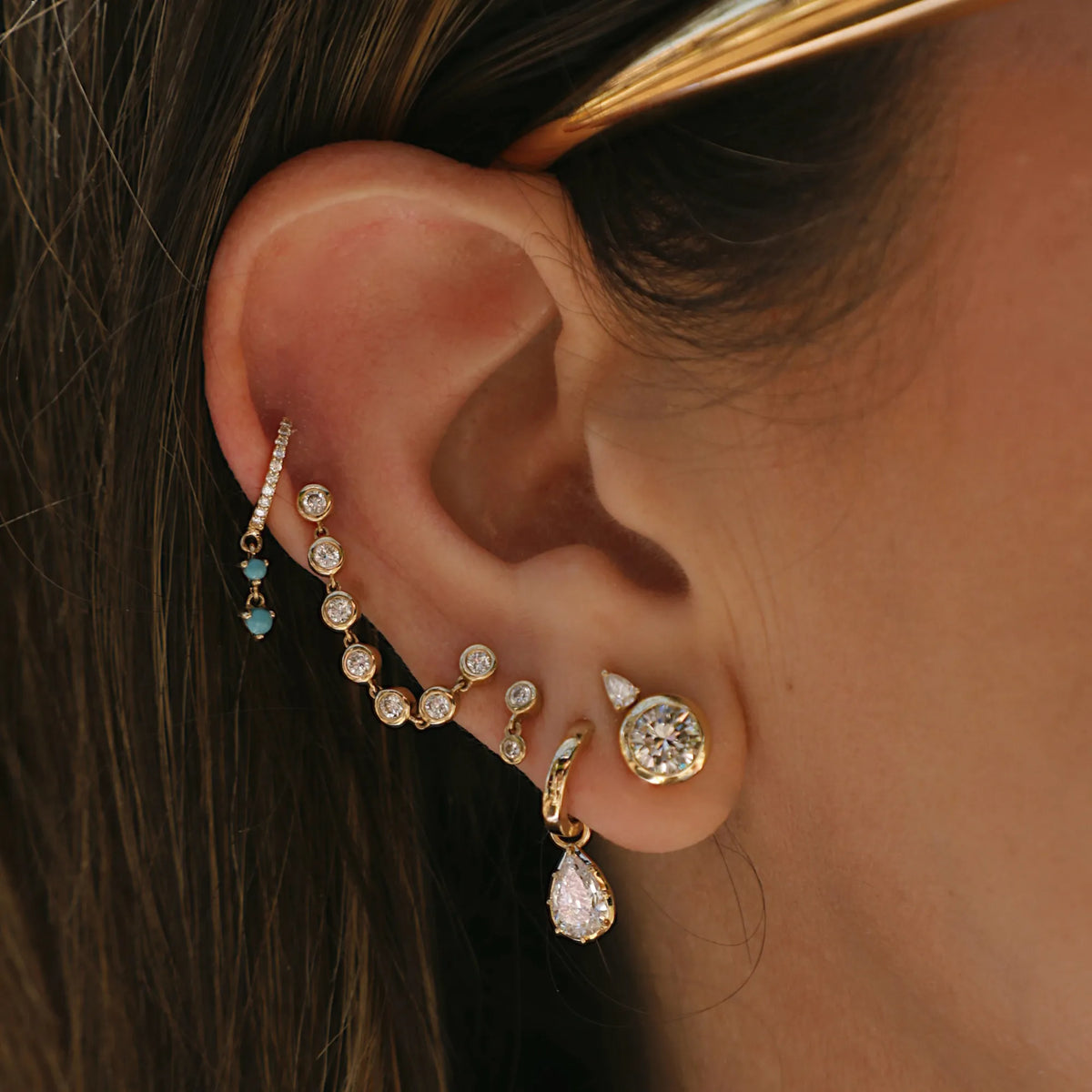 Georgian lab diamond pear drop huggies in 14k yellow gold worn in curated ear stack with bezel diamond chain earring and turquoise drop