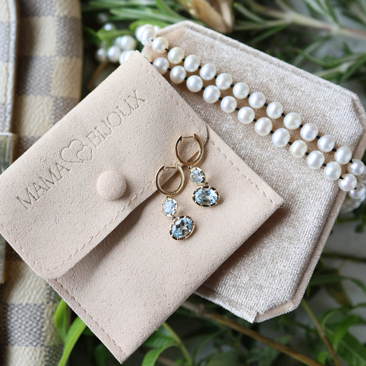 Blue topaz Georgian drop statement earrings resting on Mama Bijoux suede jewelry pouch with freshwater pearl bracelet, fine jewelry flatlay Costa Mesa