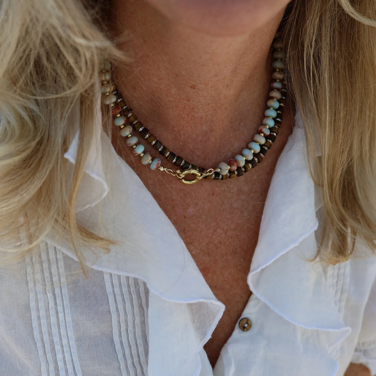 Woman wearing the Driftwood Glow tiger's eye gemstone necklace by Mama Bijoux x Isla Sol styled as a luxury layering necklace.