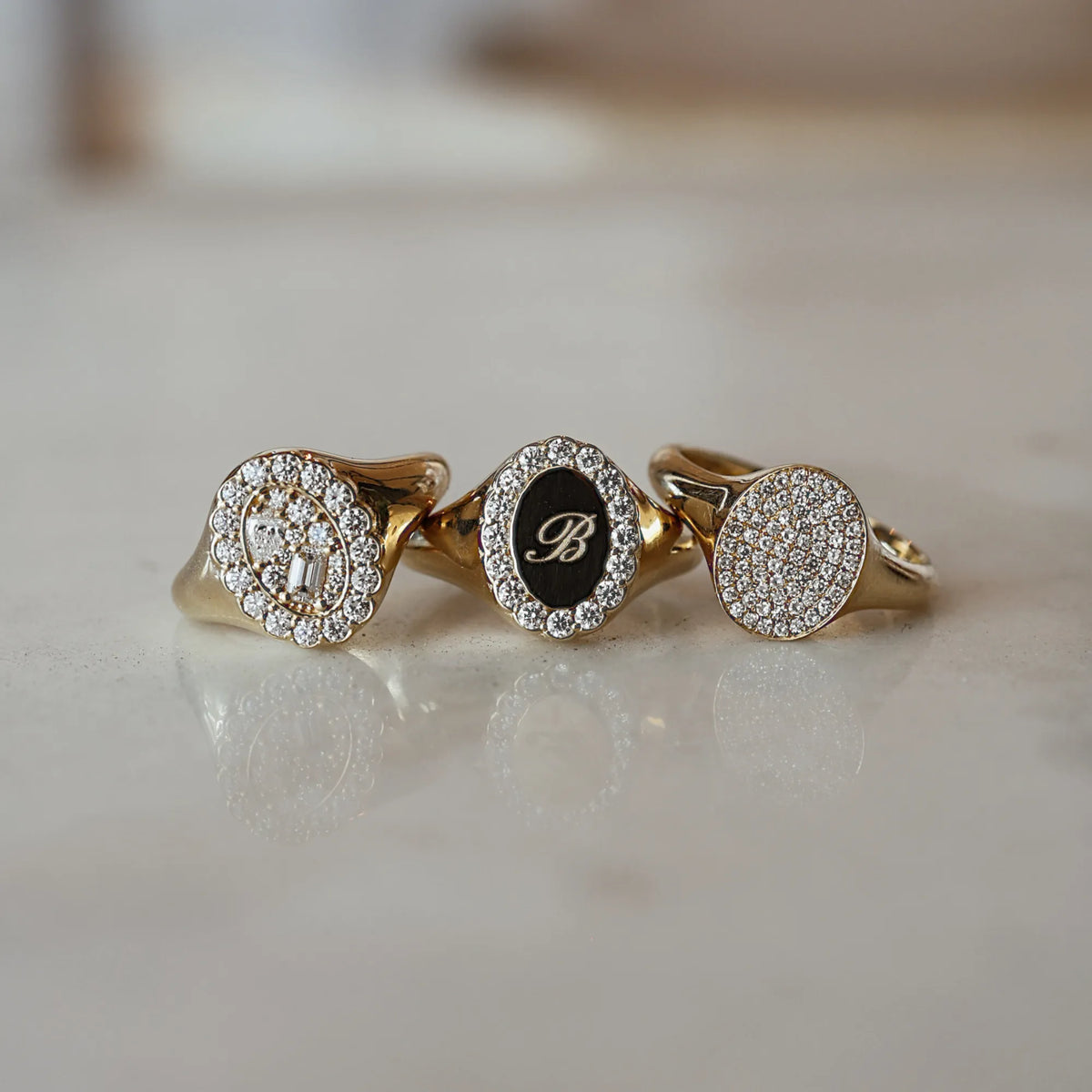 Three gold rings with diamond accents on a light surface
