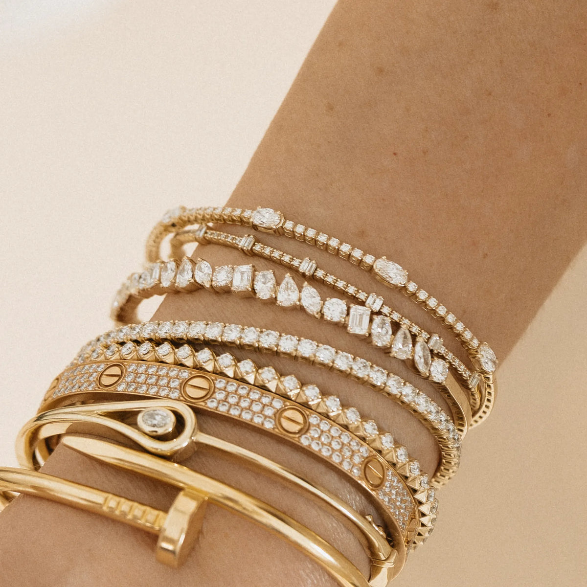 Station baguette and round diamond flexible bangle stacked with gold and diamond bracelets for an everyday luxury look.